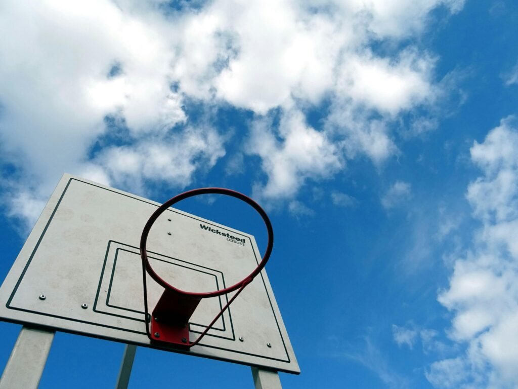Basketball hoop set against a clear blue sky with white clouds.