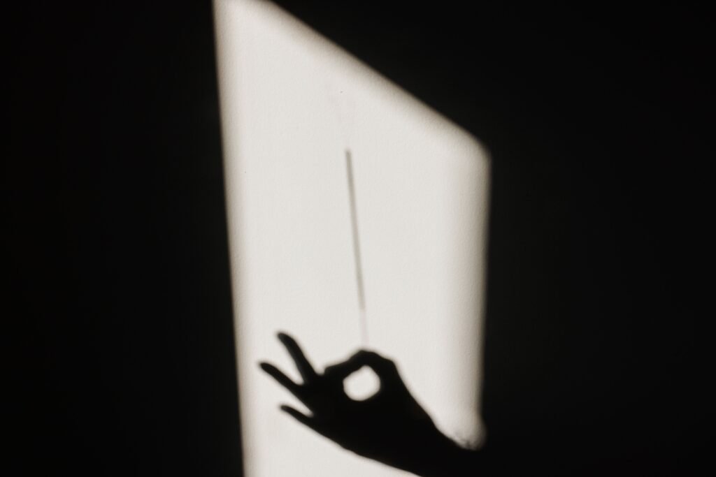 Silhouette of a hand casting an OK sign shadow on a wall, creating a dramatic light contrast.